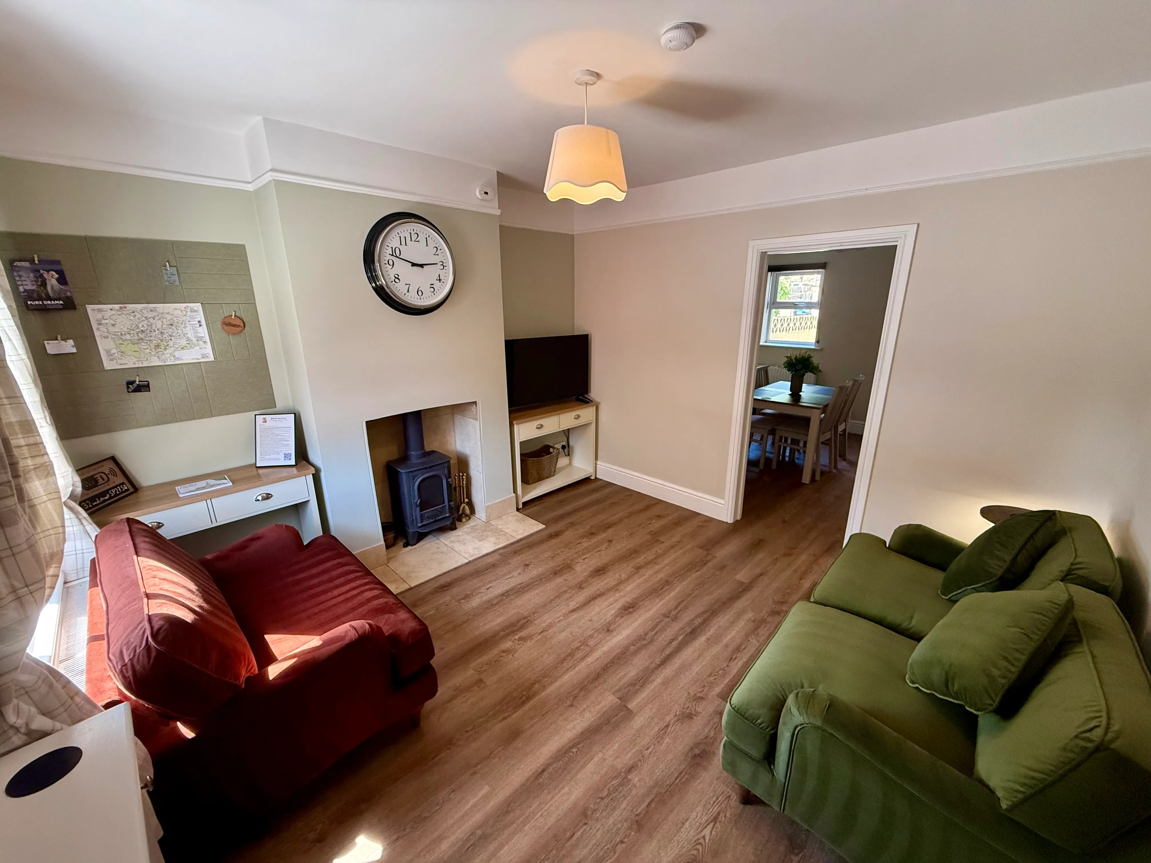 The sitting room with log burner, green and brick-red sofas and Smart TV